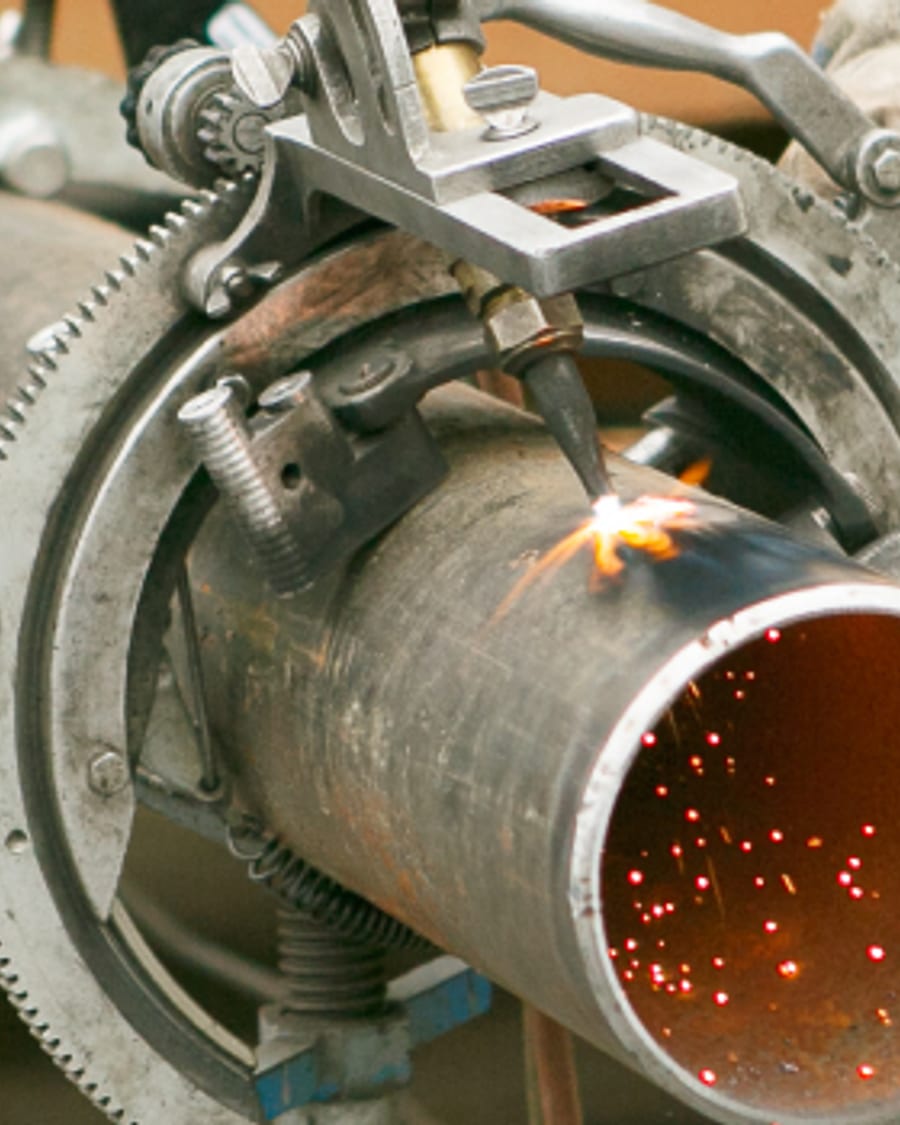 Steel pipe being cut, sparks coming off the blade, from Gormley's industrial photography